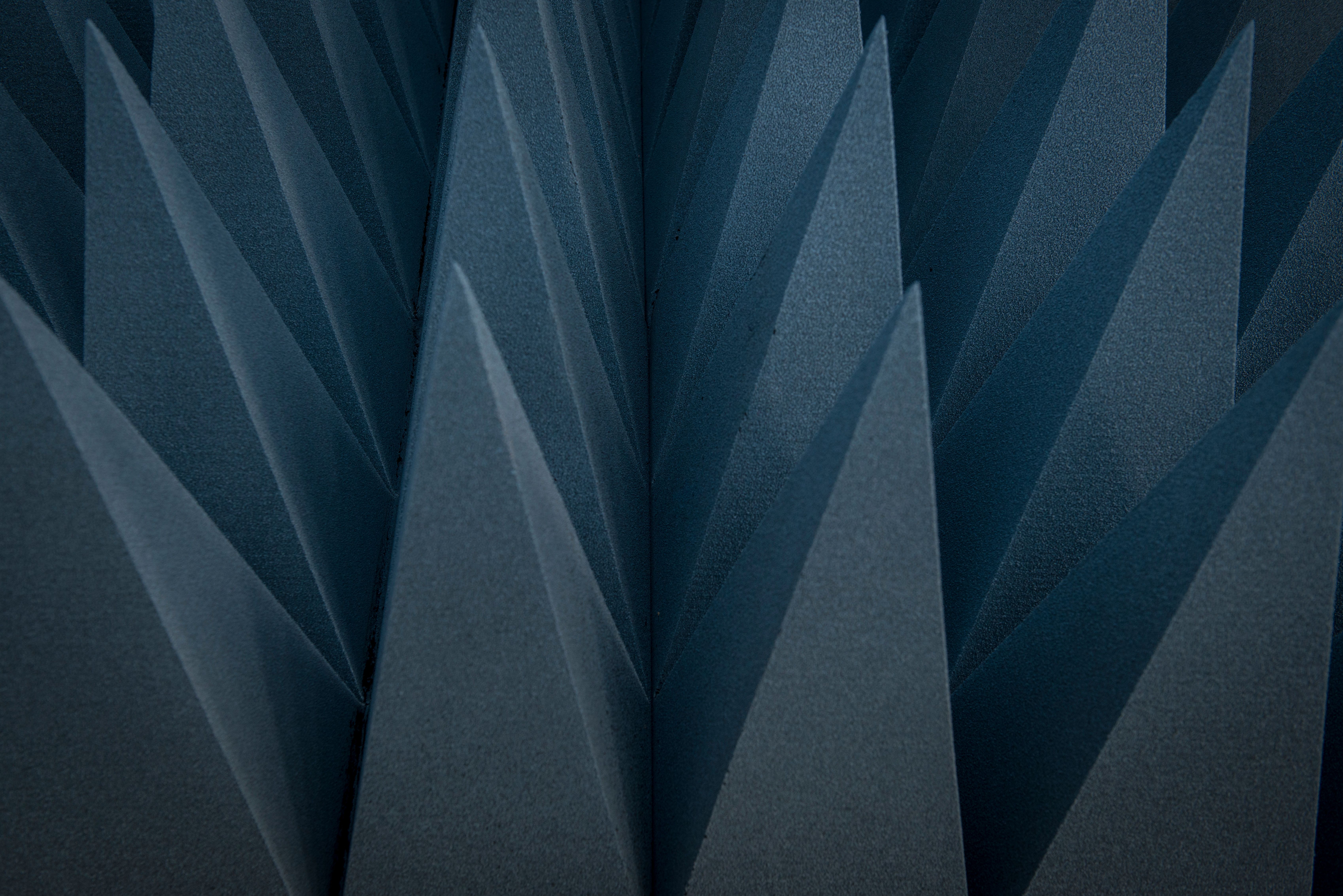 Dark blue triangular foam cones used for sound absorption create a textured wall.