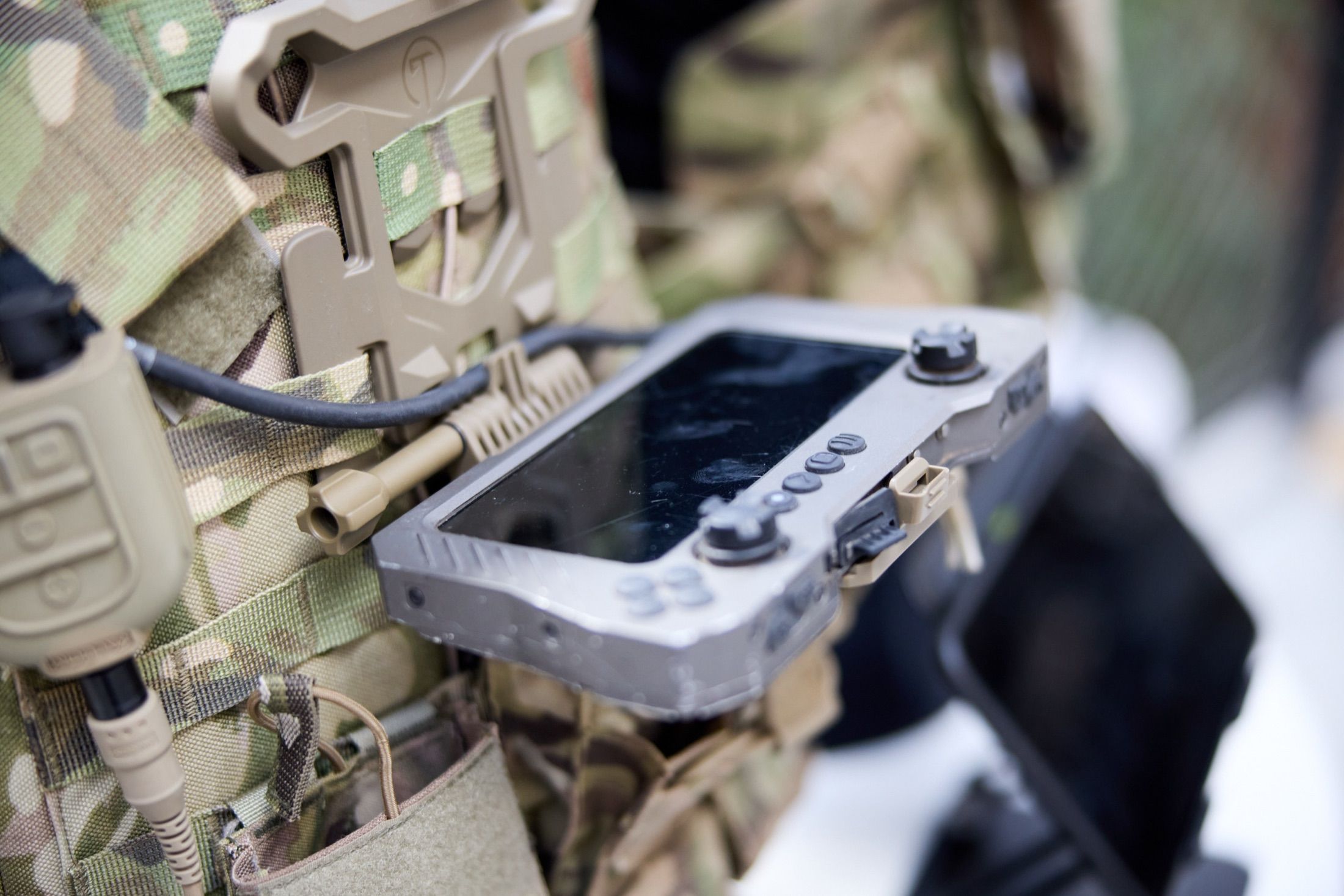 A ruggedised handheld device mounted on a soldier's tactical vest.